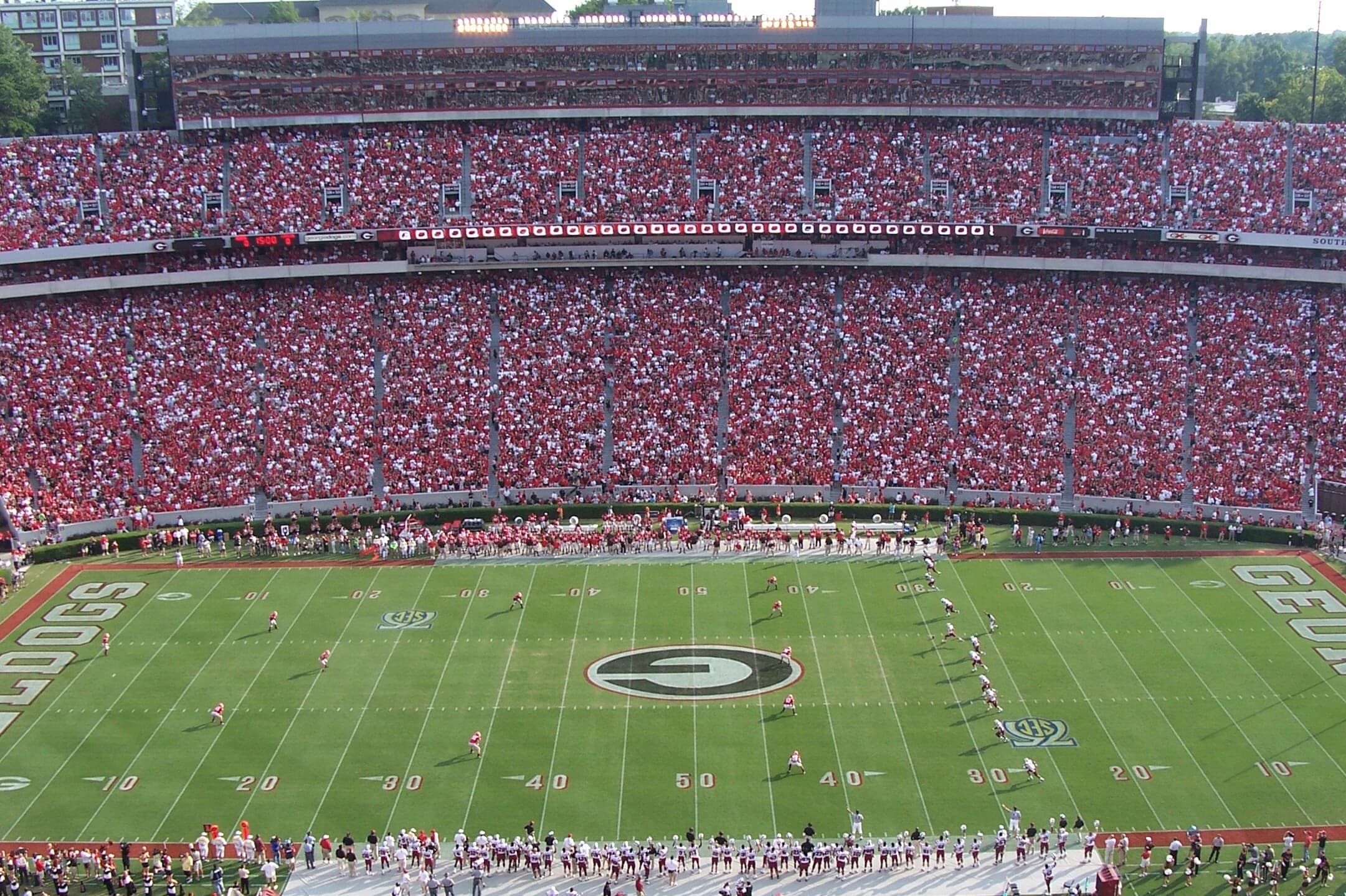 Saque inicial de un partido de fútbol americano en el Sanford Stadium de Athens, con la grada llena.